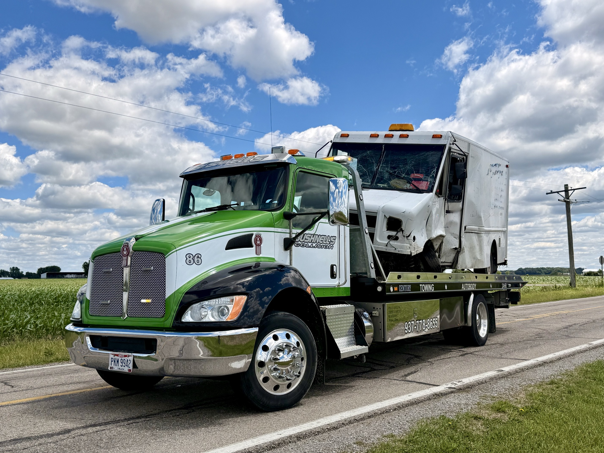 Bushnell's green flatbed tow truck loaded with a forklift